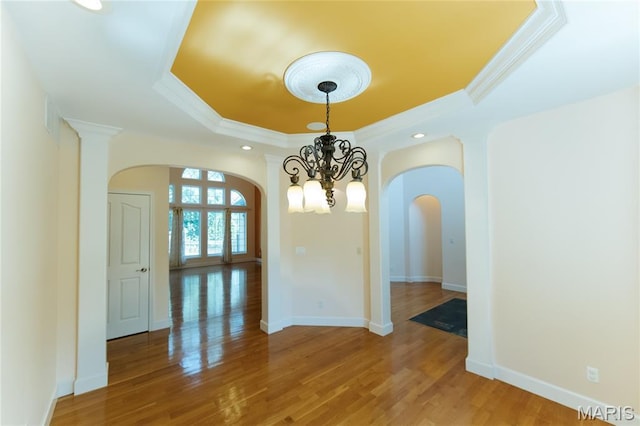 1025 Cobblestone Dr, Rolla, MO 65401 - empty room featuring a tray ceiling, arched walkways, a chandelier, light wood-type flooring, and crown molding