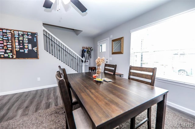 dining space with dark wood-style floors, ceiling fan, baseboards, and stairs