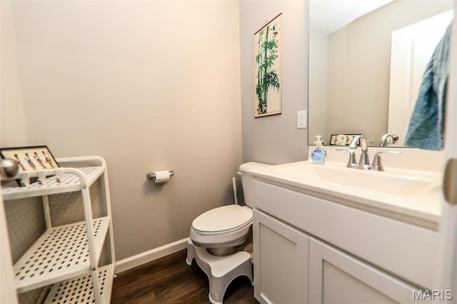 bathroom with toilet, wood finished floors, vanity, and baseboards