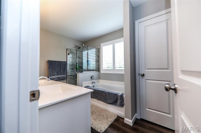 bathroom with a shower stall, wood finished floors, a garden tub, and vanity