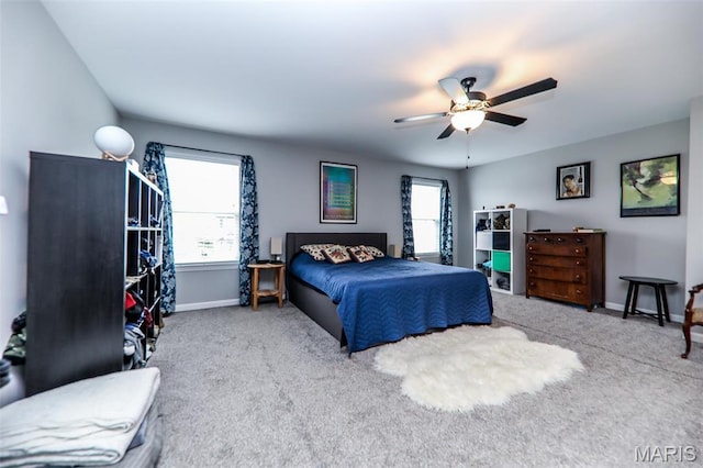 carpeted bedroom with multiple windows, baseboards, and a ceiling fan