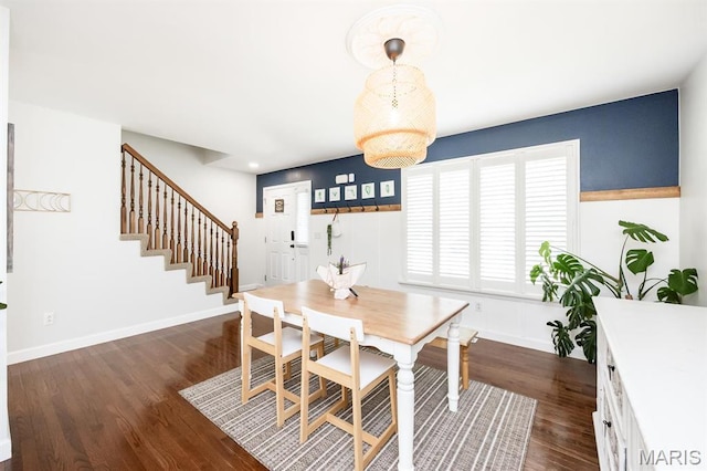 dining room featuring dark wood-style flooring, stairs, and baseboards