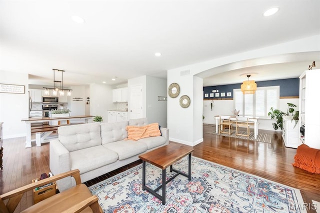 living area featuring wood finished floors, baseboards, recessed lighting, and arched walkways