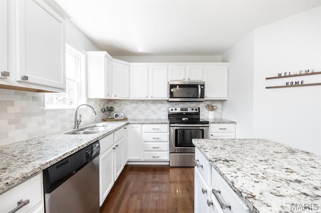 kitchen featuring appliances with stainless steel finishes, a sink, white cabinets, and light stone countertops