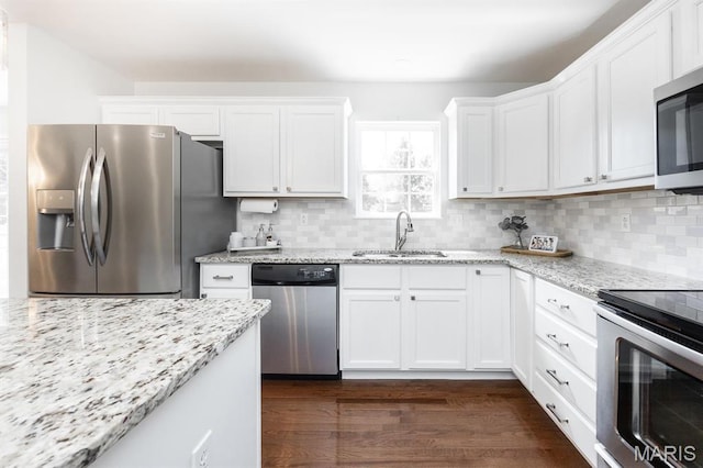 kitchen with appliances with stainless steel finishes, a sink, white cabinetry, and dark wood-style floors