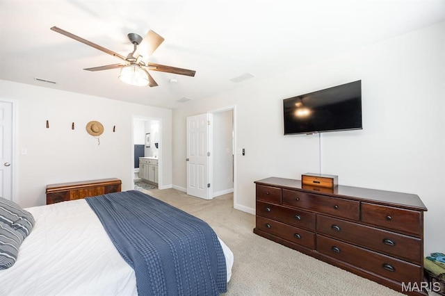 bedroom featuring light colored carpet, baseboards, a ceiling fan, and ensuite bath