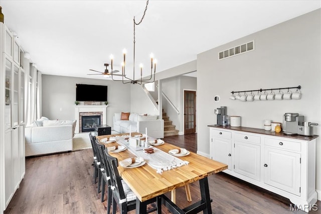 6 Bradley Ct, Troy, IL 62294 - dining room with a fireplace, ceiling fan, dark wood-style flooring, stairway, and a chandelier