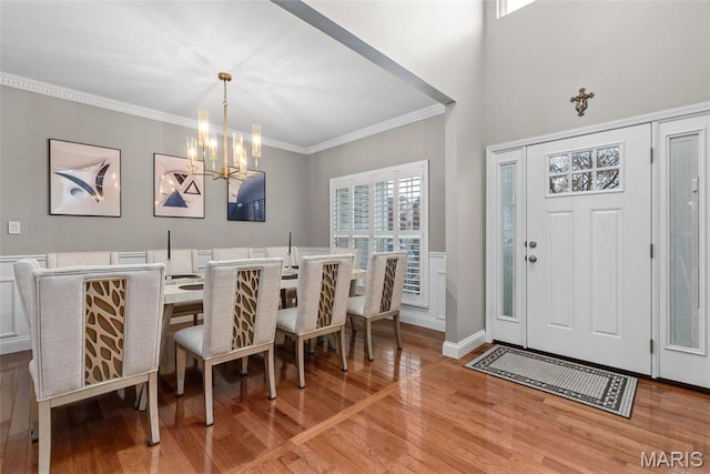 dining space featuring light wood-style flooring, a chandelier, and crown molding