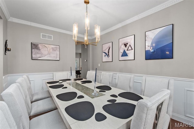 dining space with ornamental molding, a chandelier, a decorative wall, and a wainscoted wall