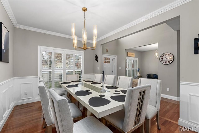 dining area featuring a chandelier, dark wood finished floors, a wainscoted wall, and ornamental molding