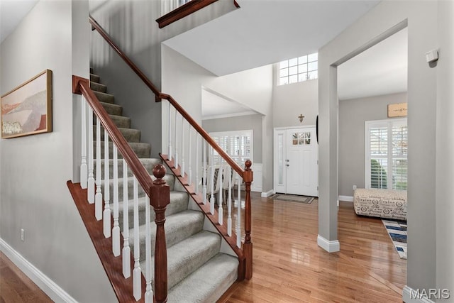 entrance foyer with wood finished floors, baseboards, stairway, and a high ceiling