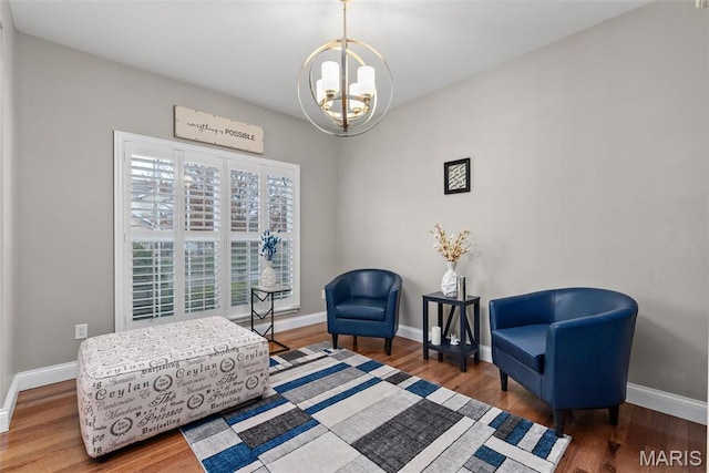 sitting room featuring a chandelier, baseboards, and wood finished floors