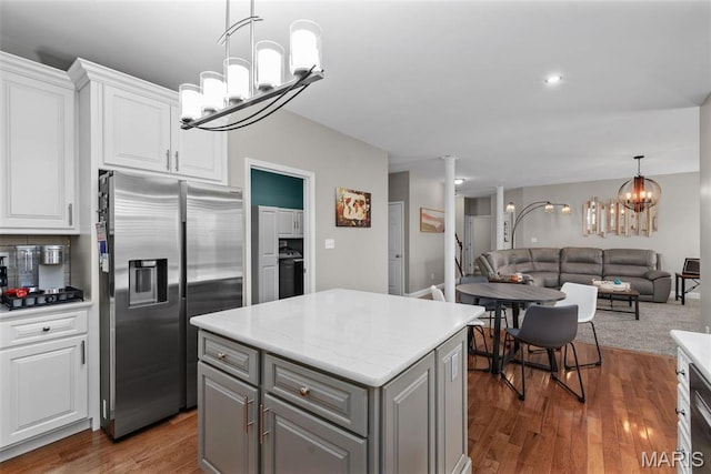 kitchen with stainless steel refrigerator with ice dispenser, a chandelier, gray cabinetry, a center island, and open floor plan