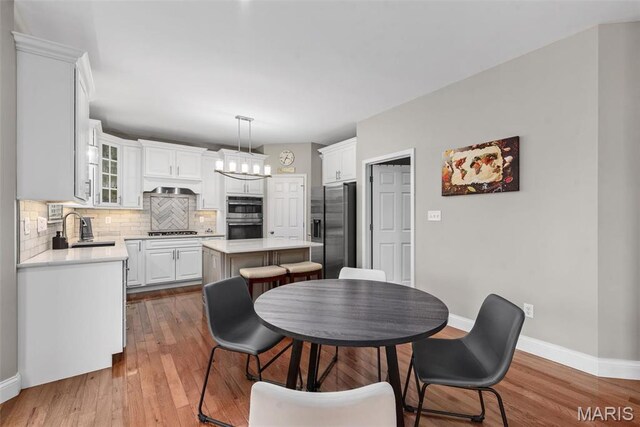 dining space with baseboards, wood finished floors, and a chandelier