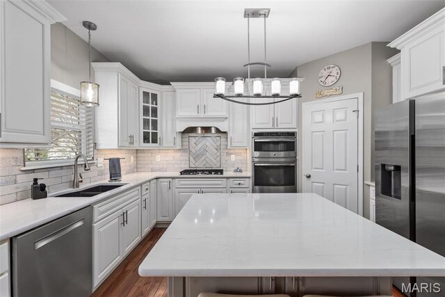 kitchen featuring appliances with stainless steel finishes, a sink, a chandelier, and white cabinets