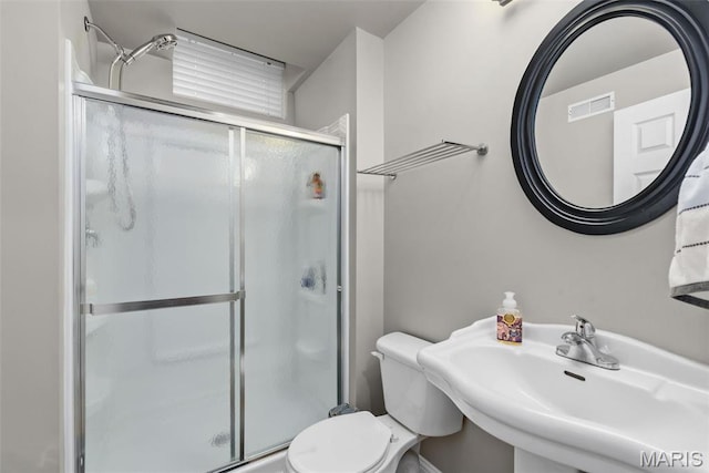 full bathroom featuring a sink, a stall shower, and toilet