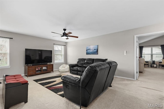 living room with light colored carpet, healthy amount of natural light, a ceiling fan, and baseboards