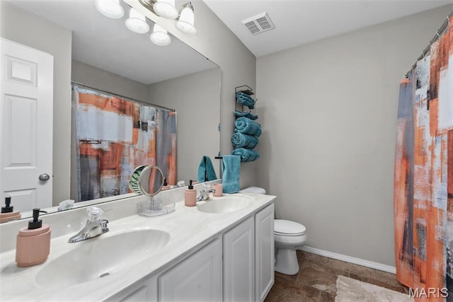 bathroom with toilet, double vanity, and baseboards