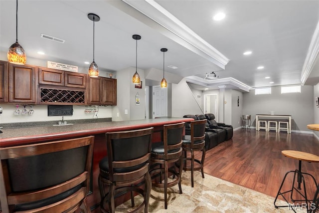 indoor wet bar featuring recessed lighting, hanging light fixtures, crown molding, baseboards, and wood finished floors