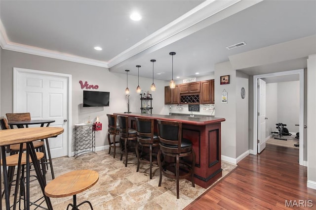indoor wet bar with baseboards, recessed lighting, crown molding, pendant lighting, and light wood-style floors