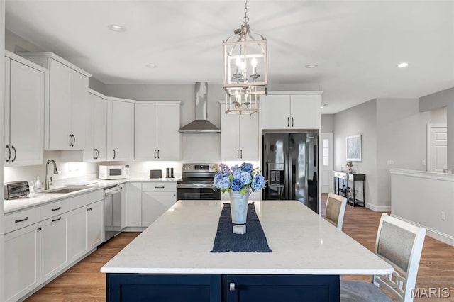 116 Dardenne Place Dr, Dardenne Prairie, MO 63368 - kitchen with stainless steel appliances, wall chimney range hood, a sink, wood finished floors, and a kitchen island