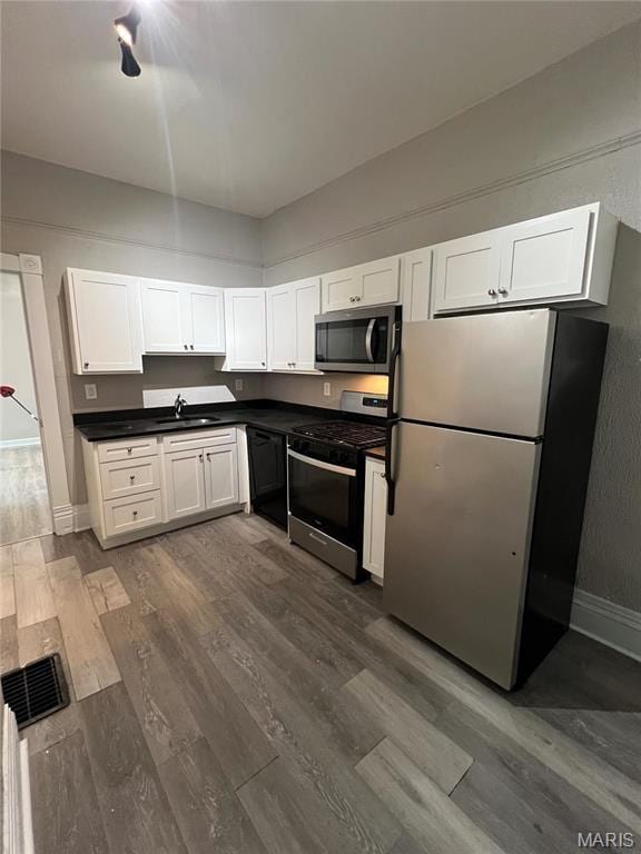 8423 Tennessee Ave, Saint Louis, MO 63125 - kitchen featuring appliances with stainless steel finishes, dark wood finished floors, white cabinets, a sink, and baseboards