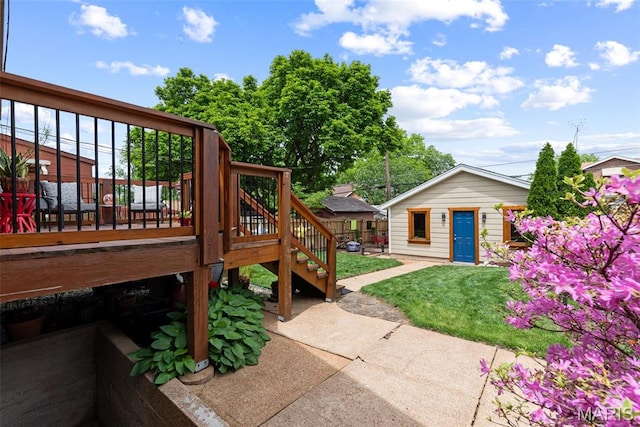 view of grassy yard with a deck, a patio area, stairway, and an outbuilding