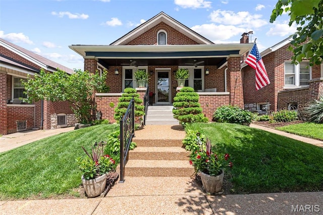 bungalow-style house with a ceiling fan, brick siding, a porch, and a front lawn