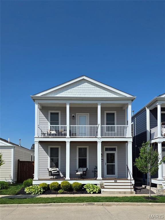 view of front of property with a balcony, covered porch, and fence