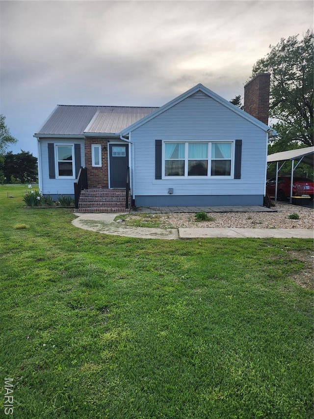 view of front of house with a chimney, metal roof, and a front yard