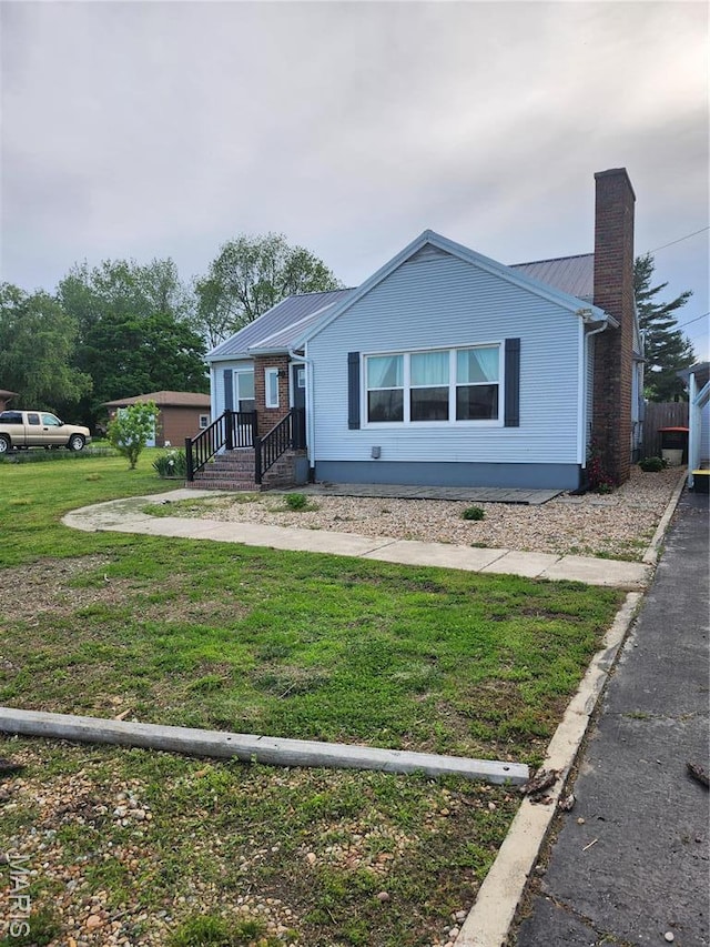 single story home with a chimney, metal roof, and a front yard