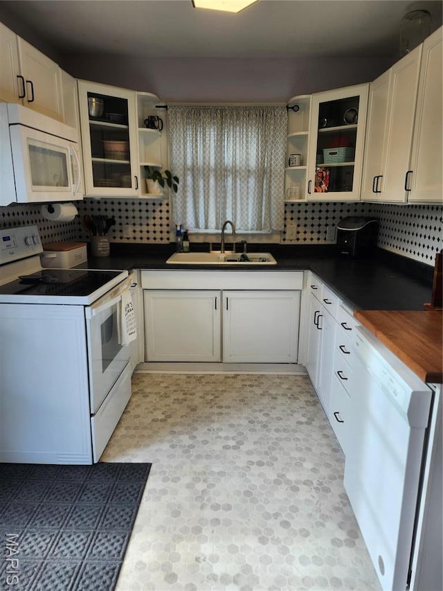 kitchen featuring white appliances, open shelves, a sink, and dark countertops