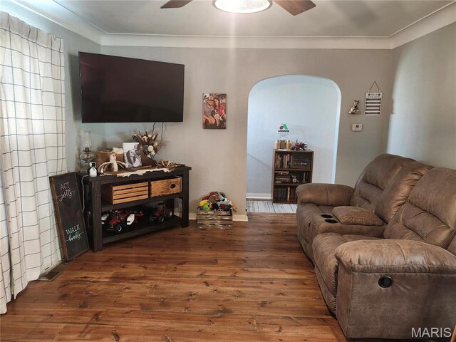 living room with ceiling fan, arched walkways, wood finished floors, ornamental molding, and baseboards