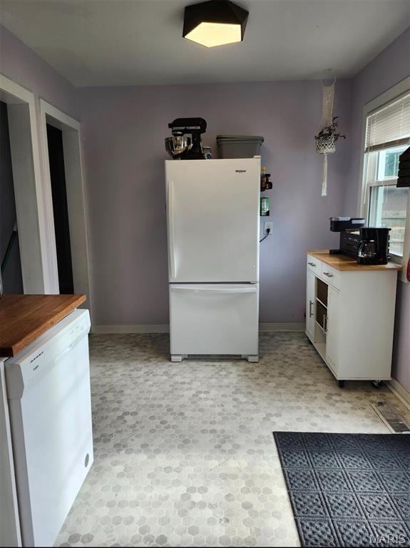 kitchen featuring white appliances, butcher block countertops, and baseboards