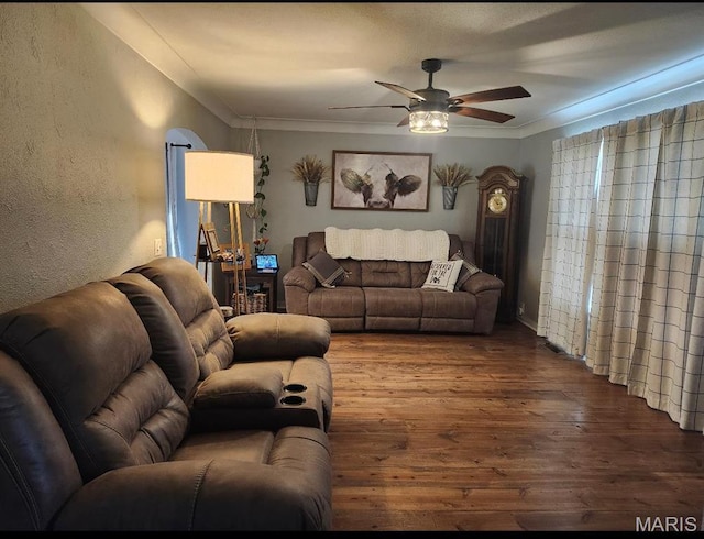 living room with wood finished floors, ceiling fan, a textured wall, and ornamental molding