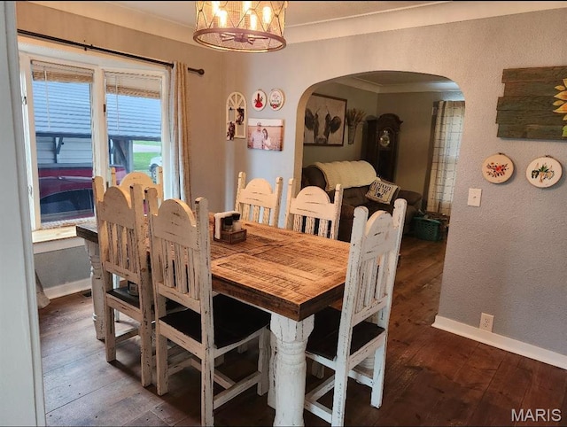 dining space with arched walkways, a chandelier, wood-type flooring, and baseboards