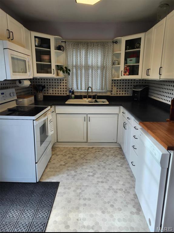 kitchen featuring white appliances, open shelves, a sink, and tasteful backsplash