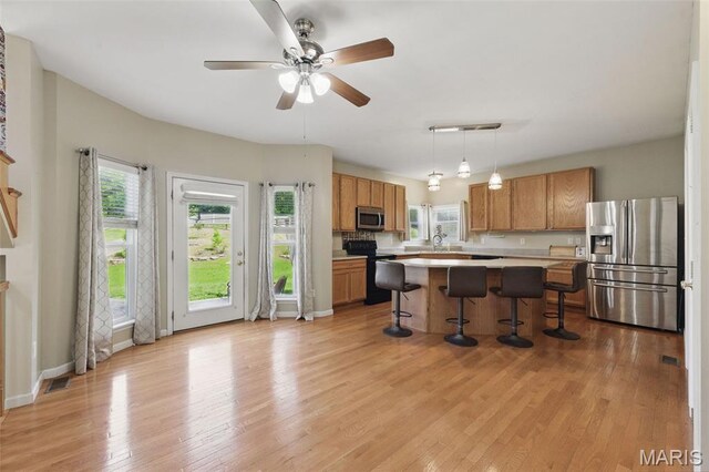 65 Snowberry Ridge Ct, Ofallon, MO 63366 - kitchen with appliances with stainless steel finishes, light countertops, a breakfast bar, light wood finished floors, and a sink
