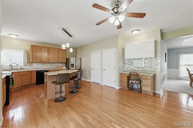 65 Snowberry Ridge Ct, Ofallon, MO 63366 - kitchen with black appliances, a kitchen bar, light wood finished floors, light countertops, and a kitchen island