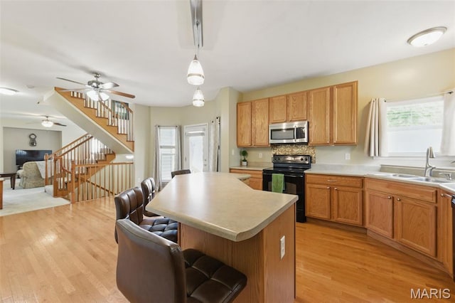 65 Snowberry Ridge Ct, Ofallon, MO 63366 - kitchen with stainless steel microwave, black electric range, a sink, a breakfast bar, and light wood-type flooring