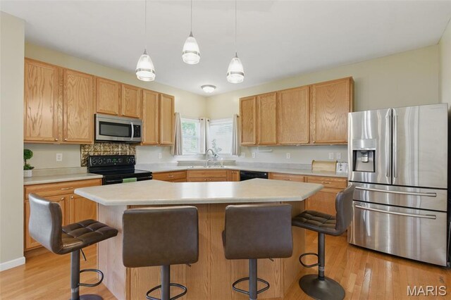 65 Snowberry Ridge Ct, Ofallon, MO 63366 - kitchen featuring black appliances, light countertops, light wood-style flooring, and a sink