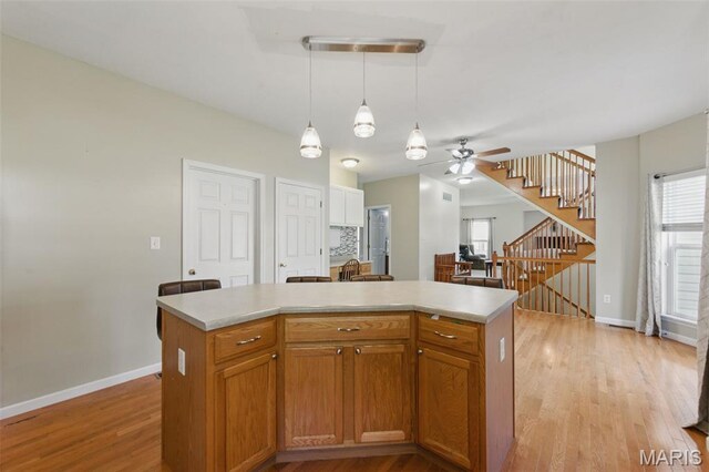 65 Snowberry Ridge Ct, Ofallon, MO 63366 - kitchen with baseboards, a ceiling fan, light countertops, light wood-style flooring, and a center island