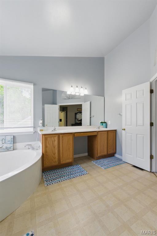 65 Snowberry Ridge Ct, Ofallon, MO 63366 - full bathroom with a garden tub, high vaulted ceiling, and vanity