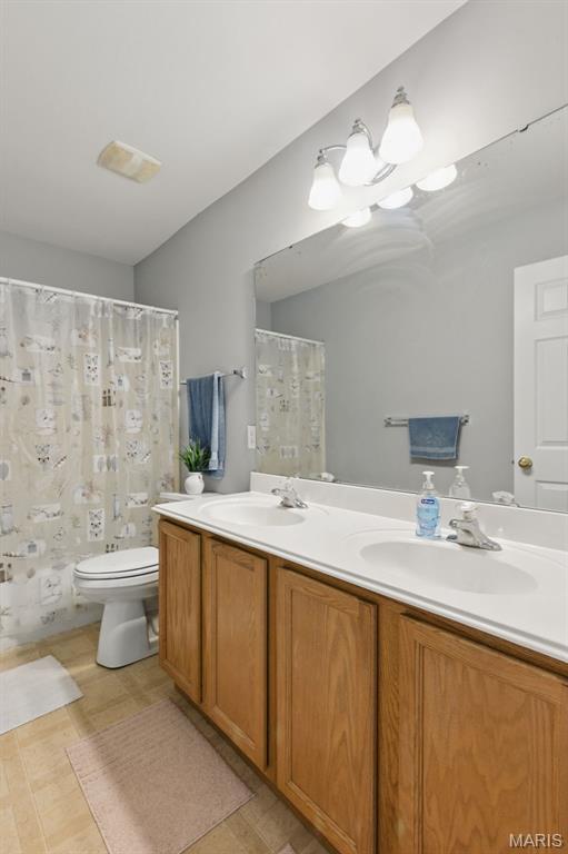65 Snowberry Ridge Ct, Ofallon, MO 63366 - bathroom featuring toilet, double vanity, and a shower with curtain