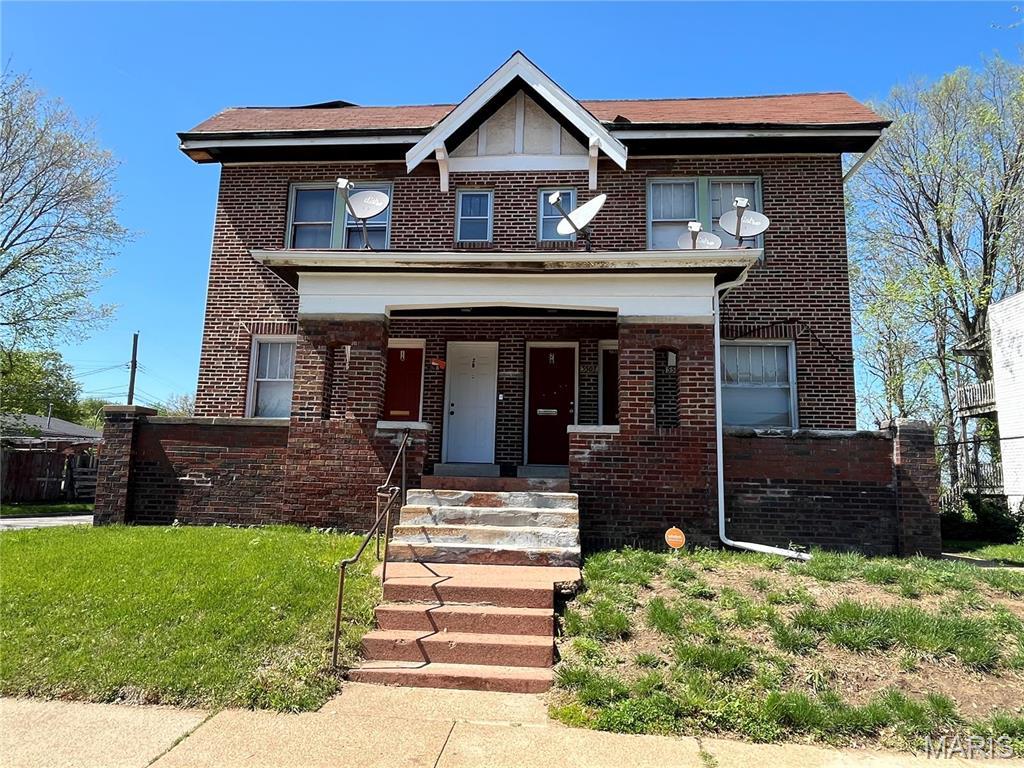 view of front of house with brick siding, a front yard, and a porch