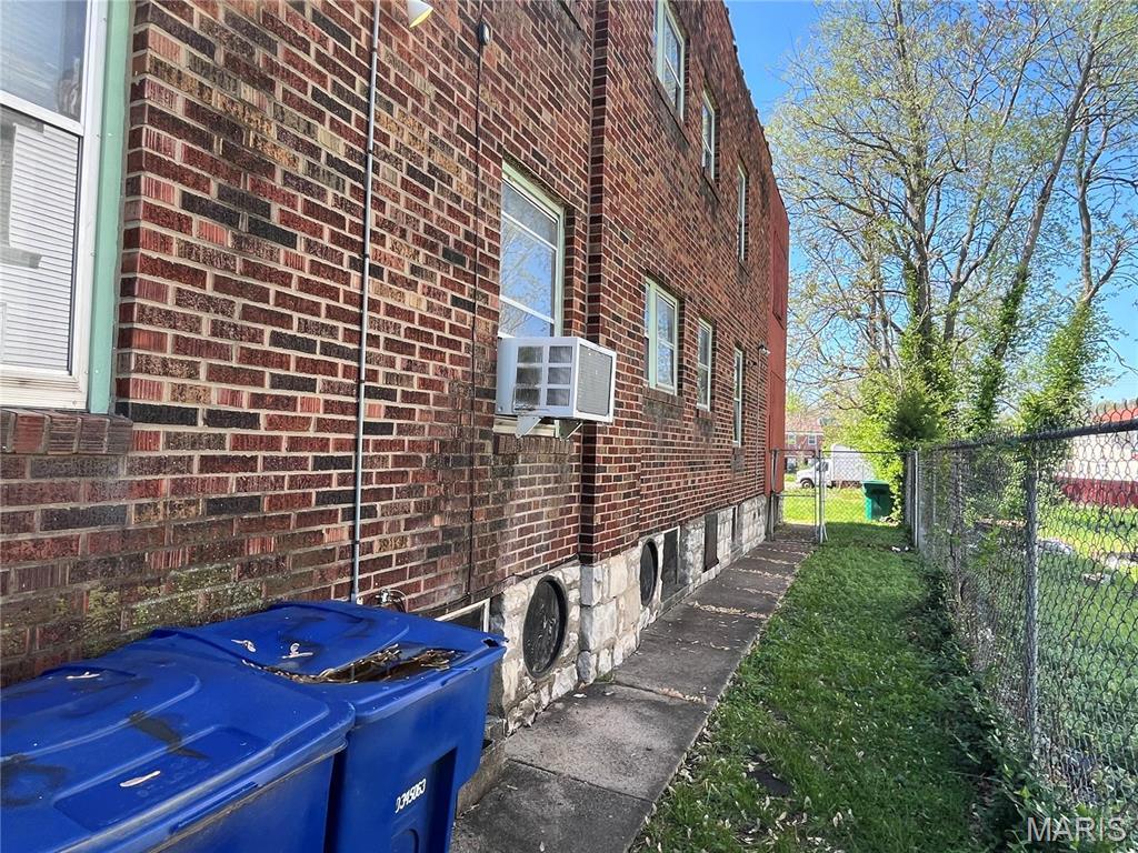 view of side of property featuring brick siding, fence, and cooling unit