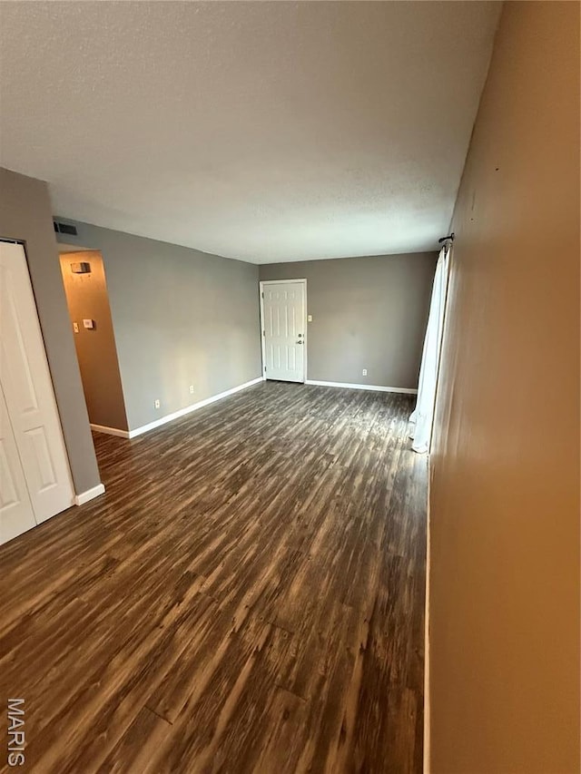 unfurnished living room featuring baseboards and dark wood finished floors