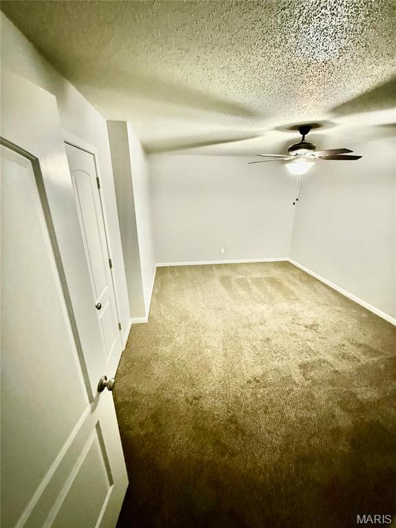 spare room featuring carpet flooring, ceiling fan, baseboards, and a textured ceiling