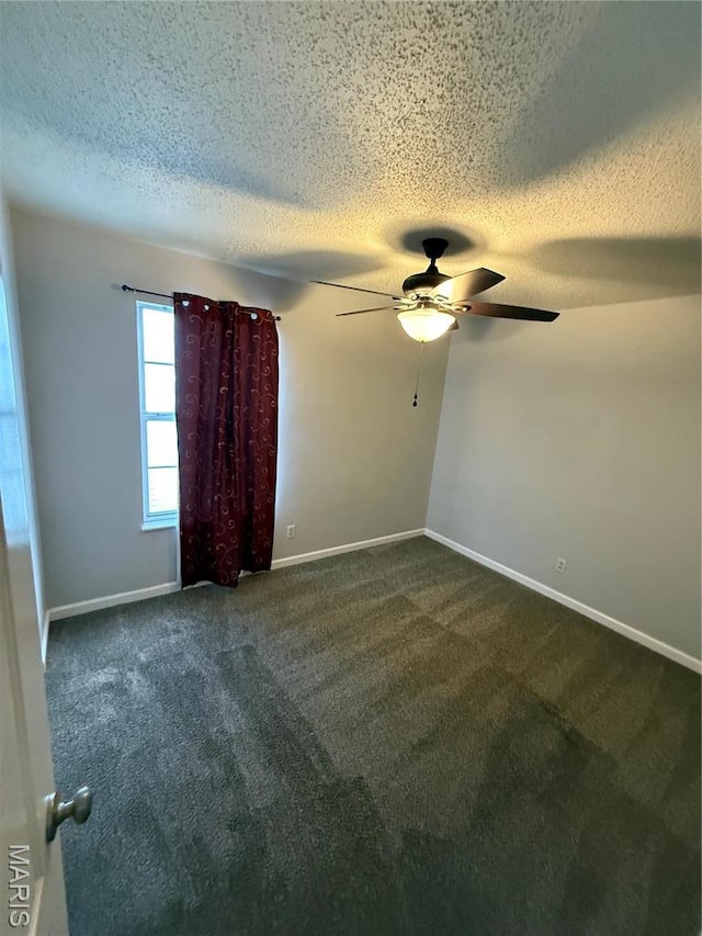 carpeted empty room with a textured ceiling, a ceiling fan, and baseboards