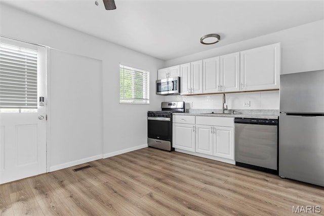 3401 Droste Rd, Saint Charles, MO 63301 - kitchen featuring appliances with stainless steel finishes, a sink, light wood-type flooring, and white cabinets